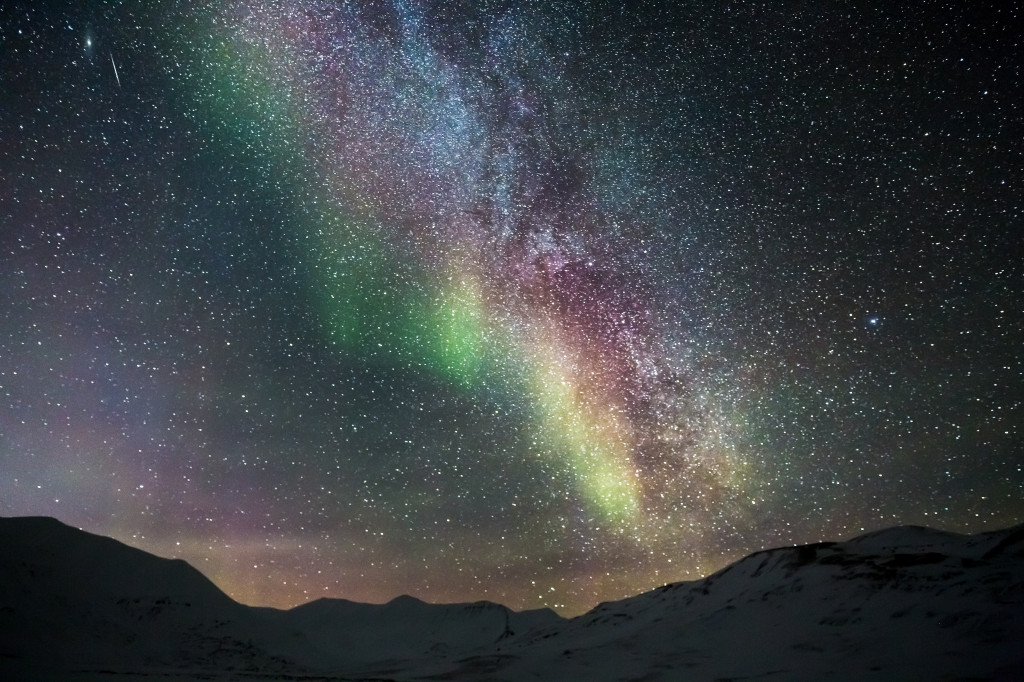 Northern lights on a dark night against Milky Way.
